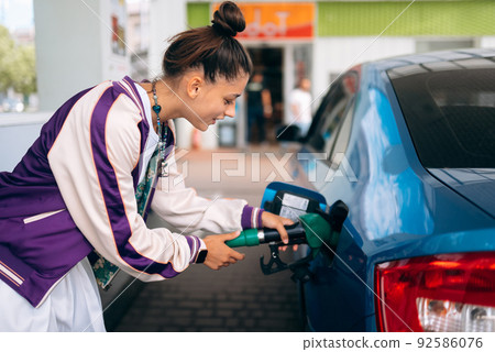 Woman filling her car with fuel at a gas station Woman filling her car with fuel at a gas station 92586076