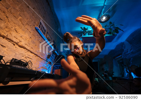 Beautiful female DJ dancing to techno in a small club Beautiful female DJ dancing to techno in a small club 92586090