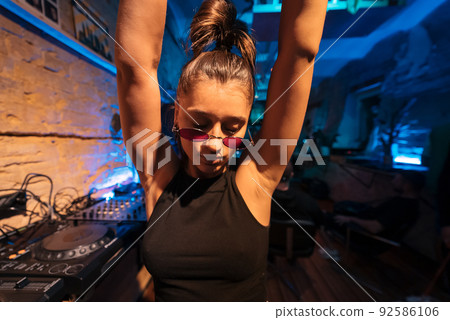 Beautiful female DJ dancing to techno in a small club 92586106