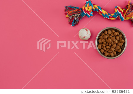 Toys -multi coloured rope, ball and dry food. Accessories for play on pink background top view 92586421