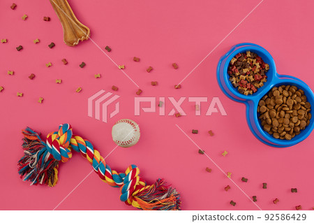 Toys -multi coloured rope, ball, dry food and bone. Accessories for play on pink background top view 92586429