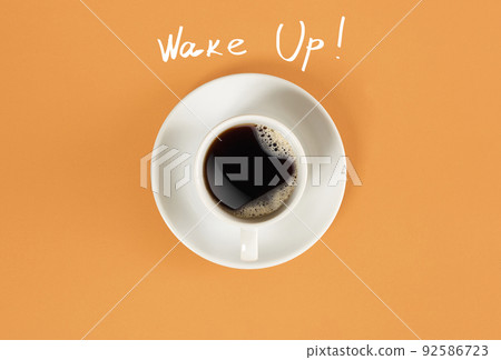 Top view of cup of black coffee and Wake Up lettering isolated on orange background 92586723