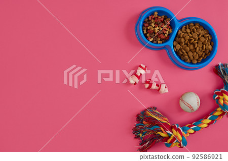 Toys -multi coloured rope, ball and dry food. Accessories for play on pink background top view 92586921