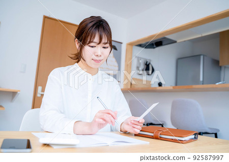Young woman living room household account book 92587997