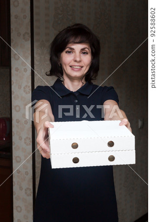 Woman housewife treats guests, holds out two boxes of pizza Woman housewife treats guests, holds out two boxes of pizza 92588602