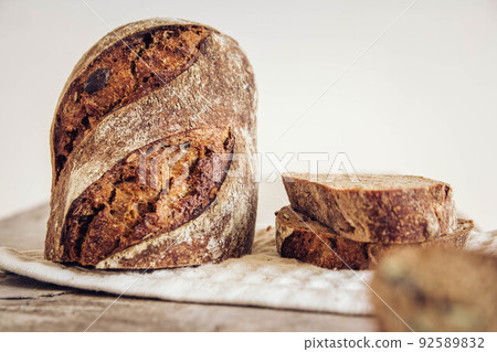 Brown fresh bread with seeds are cut into pieces on old wood background. Copy, empty space for text 92589832