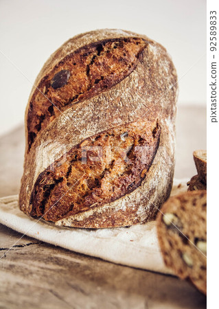 Brown fresh bread with seeds are cut into pieces on old wood background. Copy, empty space for text 92589833