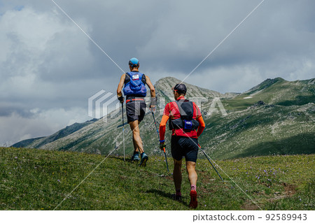 two athletes walk mountain trail during marathon two athletes walk mountain trail during marathon 92589943