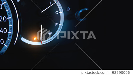 An indicator for low fuel is illuminated on a dashboard of a car with copy space An indicator for low fuel is illuminated on a dashboard of a car with copy space 92590006