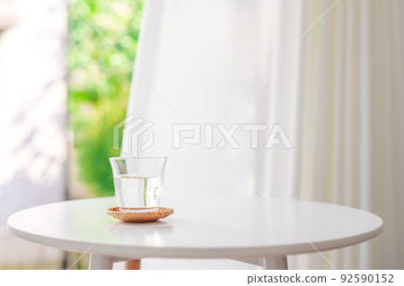 A glass of water by a bright window 92590152