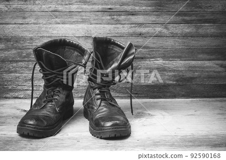 old leather black mens shoes ankle boots on wooden background front view closeup with space for your text, black and white photo 92590168