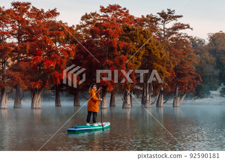 Smiling woman on stand up paddle board at the river with Taxodium trees. Traveller woman on SUP board Smiling woman on stand up paddle board at the river with Taxodium trees. Traveller woman on SUP board 92590181