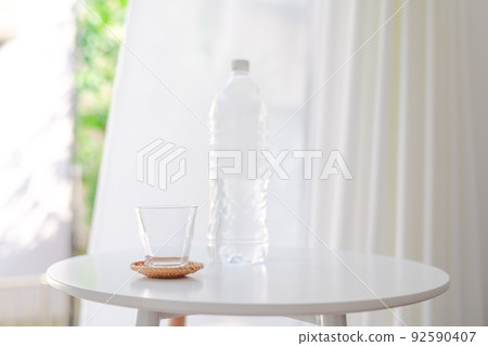 A glass by the window and a plastic bottle with water A glass by the window and a plastic bottle with water 92590407