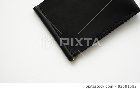Black men's money clip handmade leather wallet for cards lies on a white table. Leather goods and accessory. 92591582