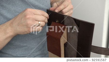 Sewing a brown leather wallet. Leather work. Sewing products by hand. Manufacture of leather goods. 92591587