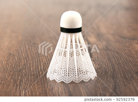 White plastic badminton shuttlecock vertically on a wooden background. White plastic badminton shuttlecock vertically on a wooden background. 92592376
