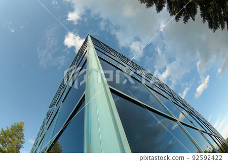 wide angle glass office building corner windows clouds sky tree reflection finance corporate business tower perspective wide angle glass office building corner windows clouds sky tree reflection finance corporate business tower perspective 92592422