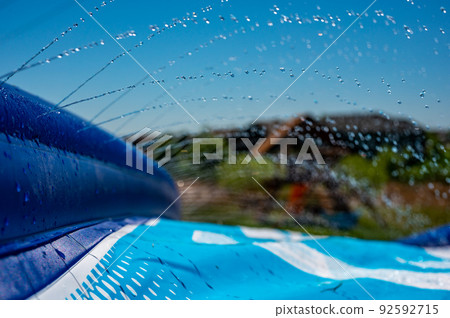 Selective focus on jets of droplets shooting out across a water slide Selective focus on jets of droplets shooting out across a water slide 92592715