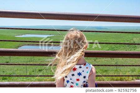 Children looking through a fence at the Feed Yard Scenic Overlook outside of Dodge City, Kansas. Children looking through a fence at the Feed Yard Scenic Overlook outside of Dodge City, Kansas. 92592756