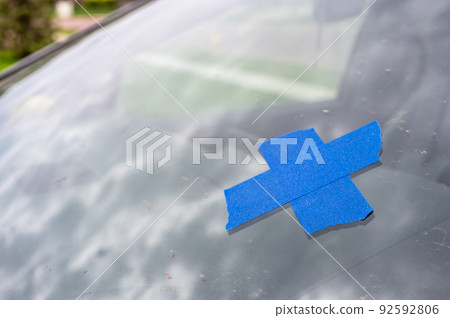 Tape covering a chip on a car windshield. Tape covering a chip on a car windshield. 92592806
