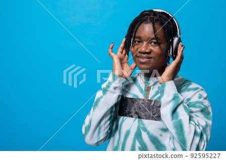 A dark-skinned man listens to music on wireless headphones. A dark-skinned man listens to music on wireless headphones. 92595227