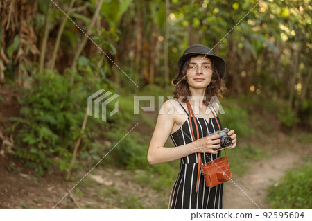 Pretty young woman holding photo camera while traveling in Africa Pretty young woman holding photo camera while traveling in Africa 92595604
