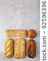 Baking background with various fresh baked whole loaves of bread flat lay on gray surface with copy space. 92596396