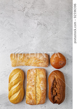 Baking background with various fresh baked whole loaves of bread flat lay on gray surface with copy space. 92596396