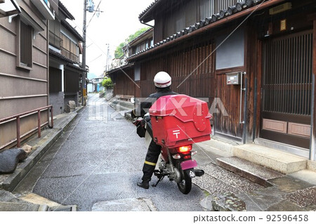 Female mail carrier in the rain 92596458