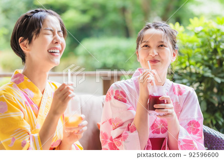 Two women drinking juice on the terrace and chatting with each other 92596600