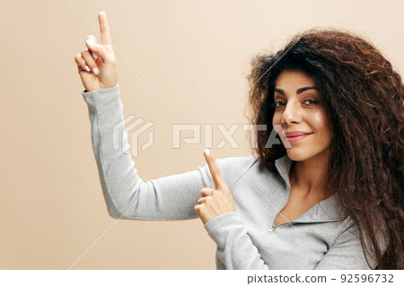 Young african american girl female in casual clothes point finger up, isolated on pastel beige wall background studio portrait. Huge sale or promo concept. Mock up copy space, cool offer for ad Young african american girl female in casual clothes point finger up, isolated on pastel beige wall background studio portrait. Huge sale or promo concept. Mock up copy space, cool offer for ad 92596732