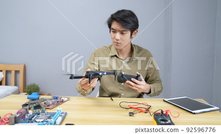 technology concept of 4k Resolution. Asian man fixing drone in room. check for damage. technology concept of 4k Resolution. Asian man fixing drone in room. check for damage. 92596776