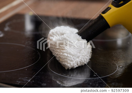 Cleaning of induction cooker with steam cleaner. Cleaning of induction cooker with steam cleaner. 92597309