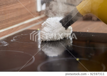 Cleaning of induction cooker with steam cleaner. Cleaning of induction cooker with steam cleaner. 92597311