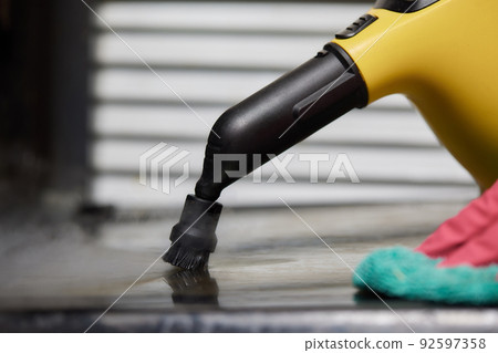 Experienced worker in rubber gloves steam-cleaning kitchen equipment. Experienced worker in rubber gloves steam-cleaning kitchen equipment. 92597358