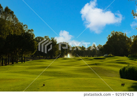 Golf course serenely under a beautiful sky Golf course serenely under a beautiful sky 92597423