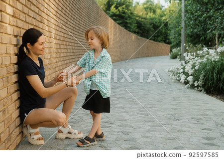 Mother and her little son holding hands on a sunny day 92597585