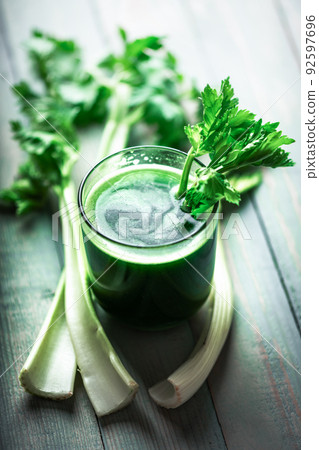 Celery fresh green juice in glass on wooden background Celery fresh green juice in glass on wooden background 92597696