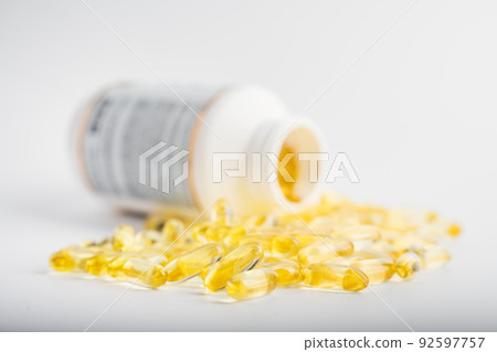 Yellow fish oil capsules in a jelly shell near the white jar Yellow fish oil capsules in a jelly shell near the white jar 92597757
