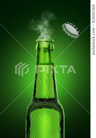 cold wet open beer bottle with smoke on green background 92600168