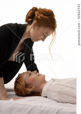 naked business - Stylish young businesswomen lying in bed one above other in topless suit 92602542
