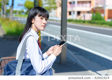 Students waiting for the bus in front of the bus stop, high school girls going to and from high school, commuting to school, residential area, urban area Students waiting for the bus in front of the bus stop, high school girls going to and from high school, commuting to school, residential area, urban area 92602924