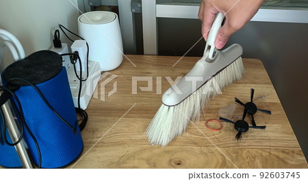 Hand Sweeping Dust With A Broom on wooden table Housekeeping Concept 92603745