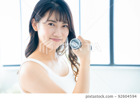 Young woman doing muscle training with dumbbells 92604594