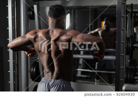 Handsome afro american man posing showing back muscles in gym.  92604930