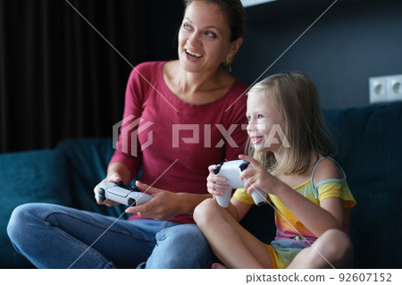 Mother and child girl playing video games Mother and child girl playing video games 92607152