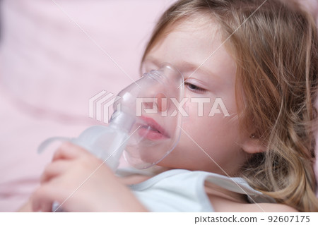 Little baby girl with oxygen mask lying on hospital bed or at home 92607175