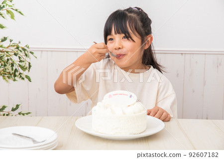A girl chewing on a cake birthday 92607182