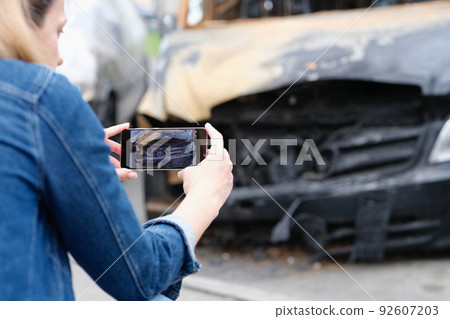 Woman insurance agent or reporter journalist taking pictures of burnt car Woman insurance agent or reporter journalist taking pictures of burnt car 92607203