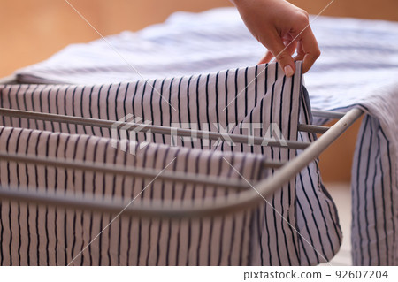 Woman hands hanging clothes to dry on dryer Woman hands hanging clothes to dry on dryer 92607204